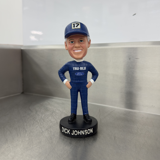 Bobblehead figure of Dick Johnson in racing suit and cap with 'TRU-BLU' and 'Ford' branding on a metallic surface.